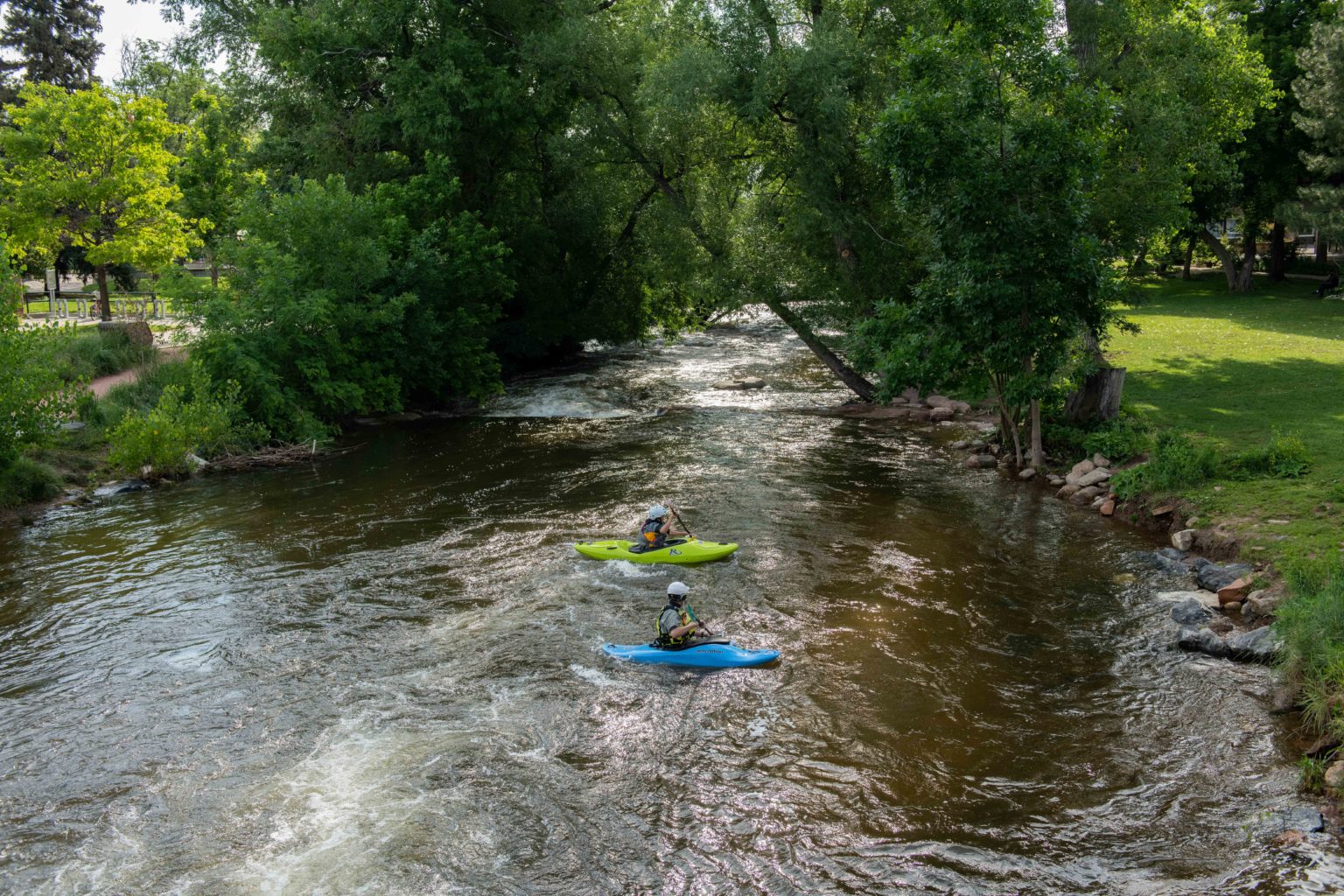 Aerial view of a man and woman kayaking in a stream.