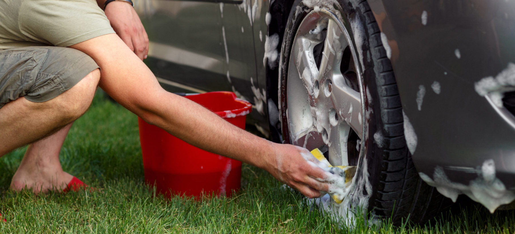 Persona lavando un coche con agua jabonosa.