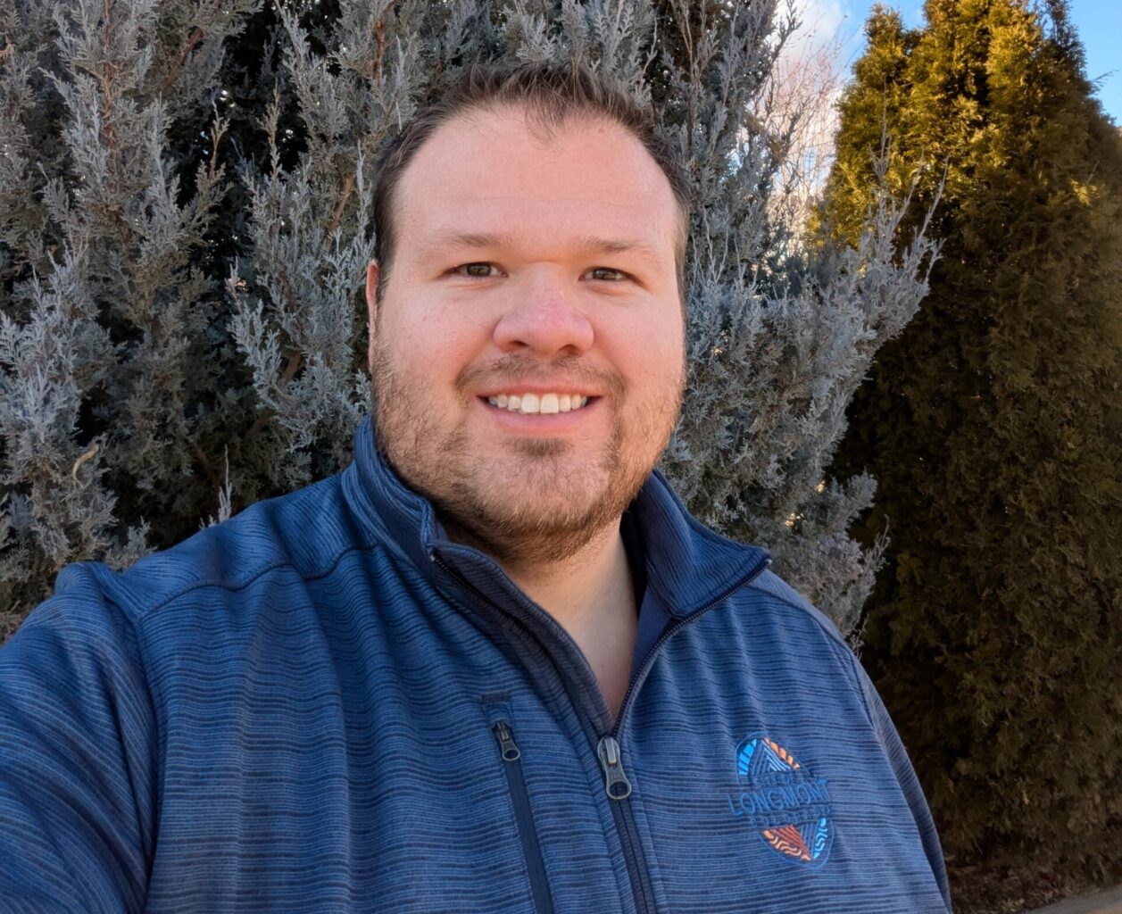 Headshot of a man standing outside wearing a city branded polo.