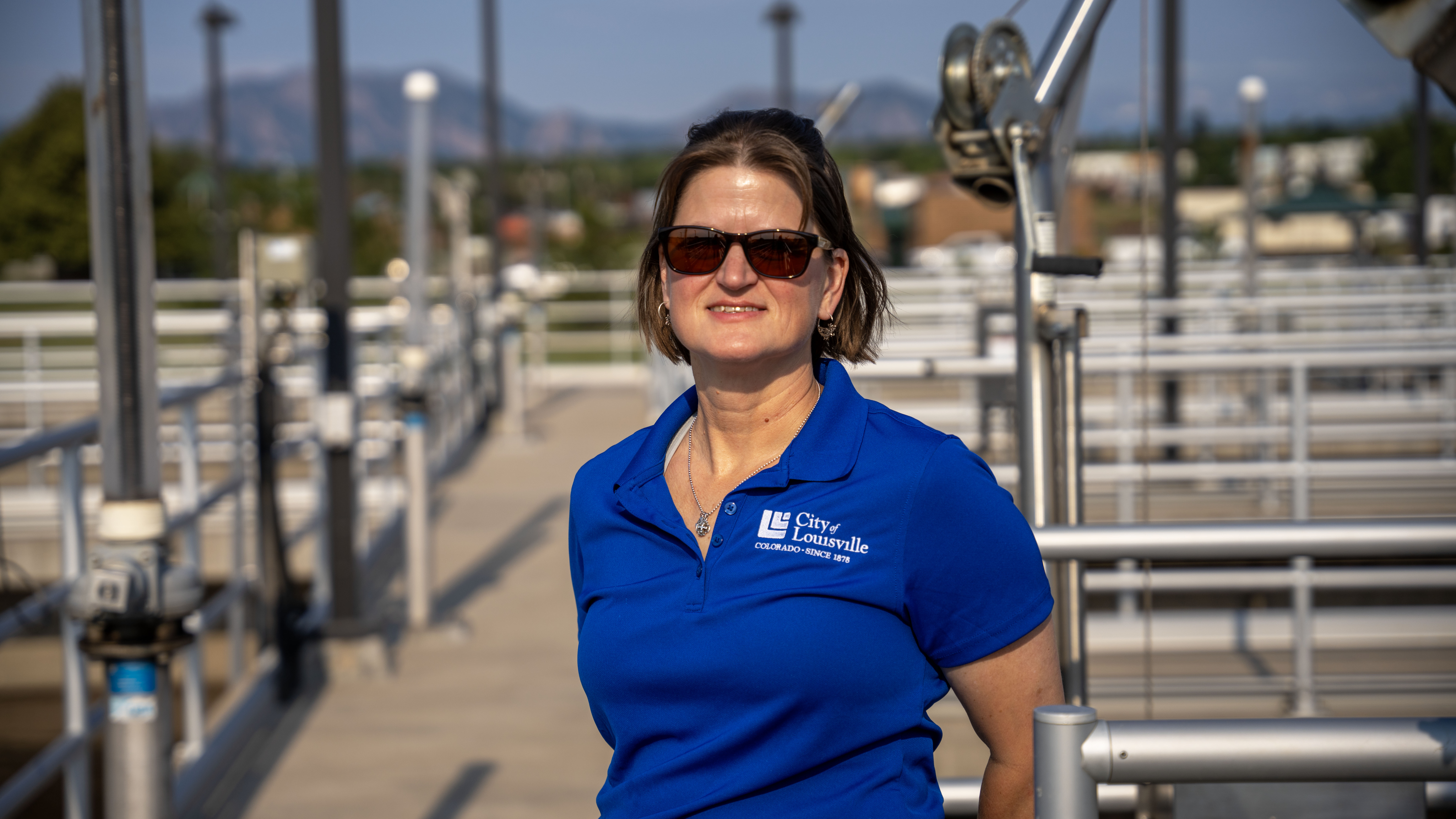 A woman with City of Louisville uniform stands near a water treatment facility walkway.