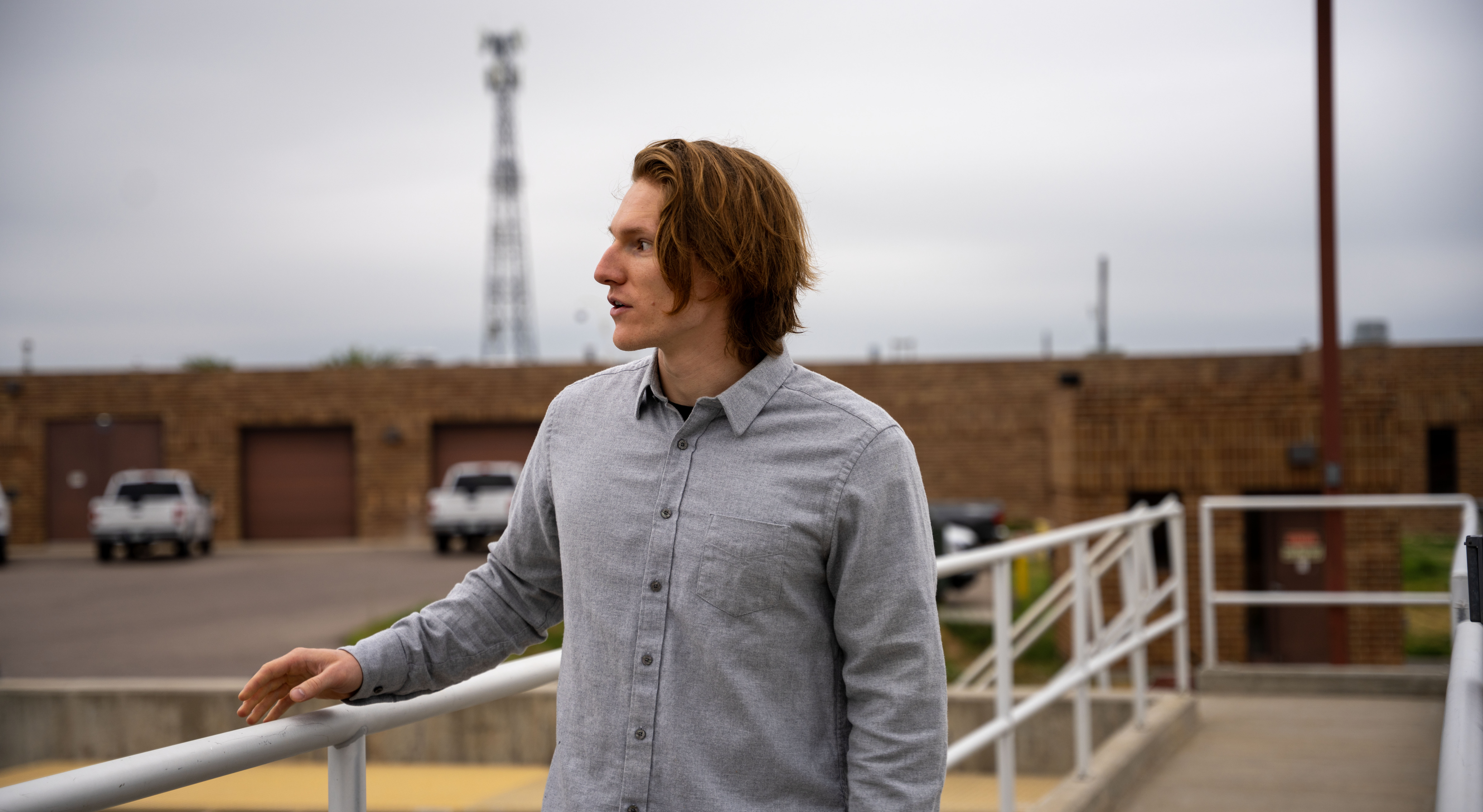 A man standing by a railing looks into the distance.