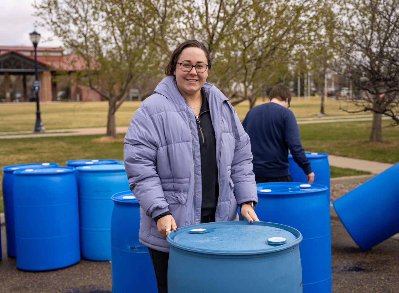 A woman poses with a 55-gallon blue barrel.